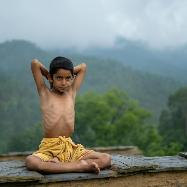 A calm person meditating outdoors with nature in the background.